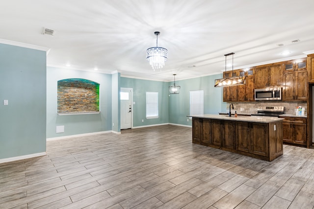 kitchen with appliances with stainless steel finishes, light hardwood / wood-style floors, an island with sink, backsplash, and pendant lighting