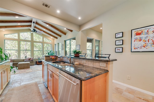 kitchen featuring a large island with sink, sink, dishwasher, ceiling fan, and dark stone counters