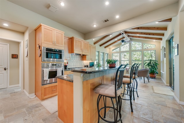 kitchen featuring a kitchen island, light brown cabinets, vaulted ceiling with beams, a kitchen breakfast bar, and ceiling fan