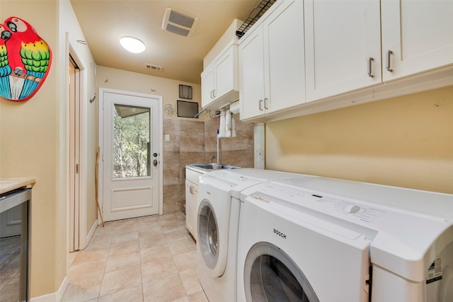 clothes washing area with cabinets, independent washer and dryer, and light tile patterned flooring