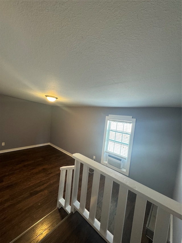 stairs with a textured ceiling, cooling unit, and hardwood / wood-style floors