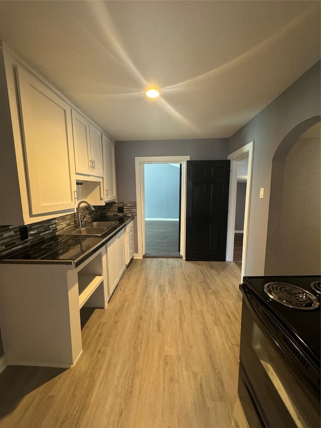 kitchen featuring decorative backsplash, white cabinets, black range with electric cooktop, light hardwood / wood-style flooring, and sink