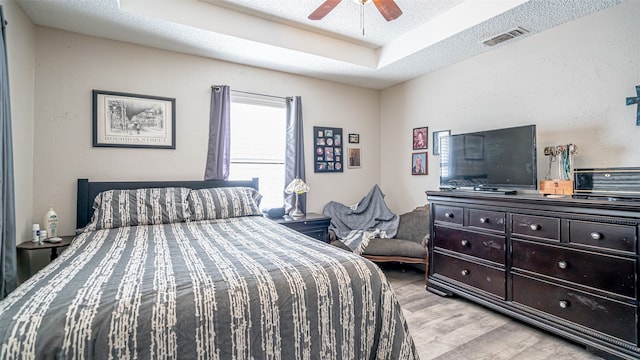 bedroom with a textured ceiling, light wood-type flooring, and ceiling fan