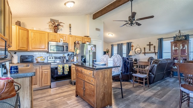 kitchen featuring dark wood-type flooring, a center island, appliances with stainless steel finishes, a textured ceiling, and ceiling fan