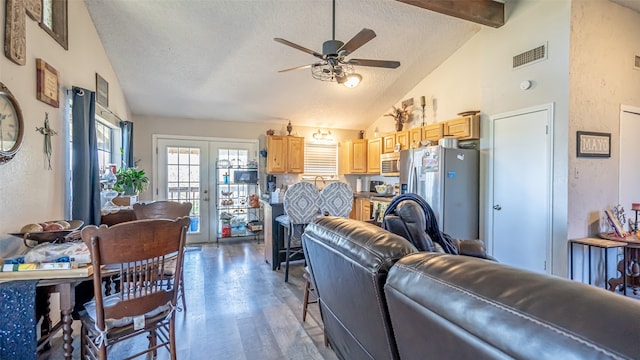 living room featuring hardwood / wood-style floors, ceiling fan, a textured ceiling, beamed ceiling, and french doors