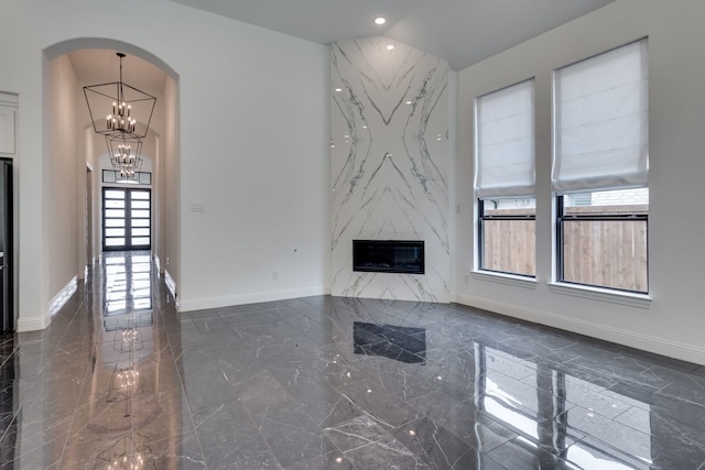 6709 Elderberry Way, Flower Mound, TX 76226 - unfurnished living room featuring dark marble finish flooring, a chandelier, arched walkways, a high end fireplace, and recessed lighting