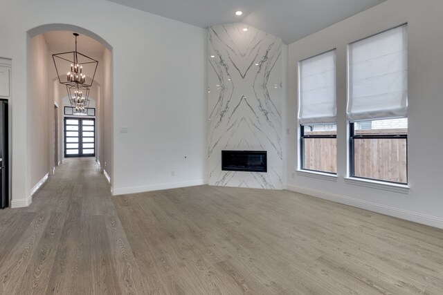 6709 Elderberry Way, Flower Mound, TX 76226 - unfurnished living room featuring a fireplace, wood finished floors, arched walkways, a chandelier, and recessed lighting