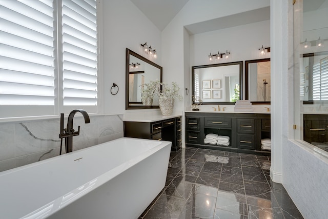 bathroom with a bathing tub, vaulted ceiling, and vanity