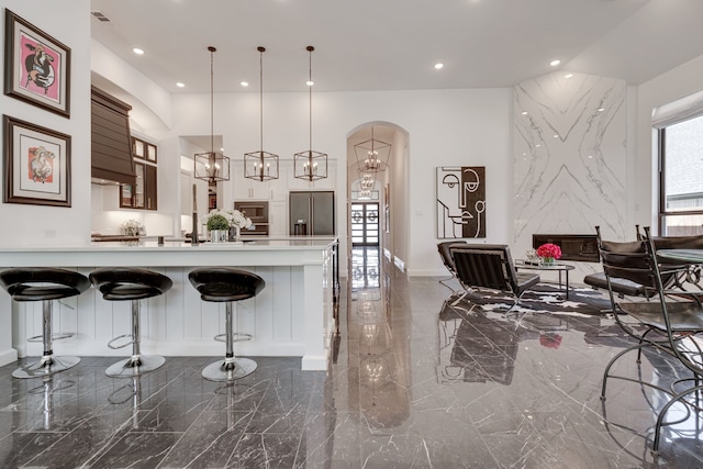 kitchen featuring pendant lighting, a breakfast bar area, stainless steel appliances, and a high end fireplace