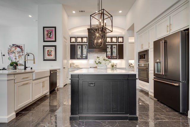 kitchen with a kitchen island, stainless steel appliances, sink, hanging light fixtures, and white cabinetry