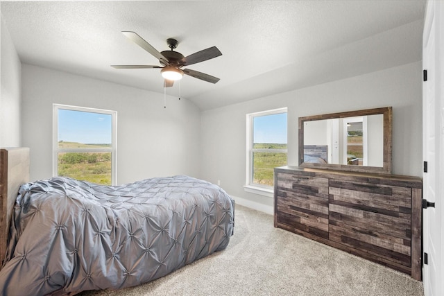 carpeted bedroom with ceiling fan, a textured ceiling, multiple windows, and lofted ceiling