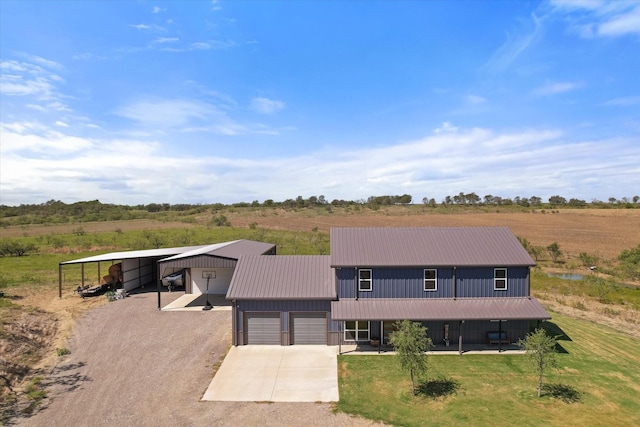 view of front facade with a front yard, a rural view, a carport, and a garage