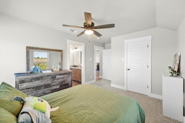 bedroom with vaulted ceiling, ceiling fan, light carpet, and ensuite bath