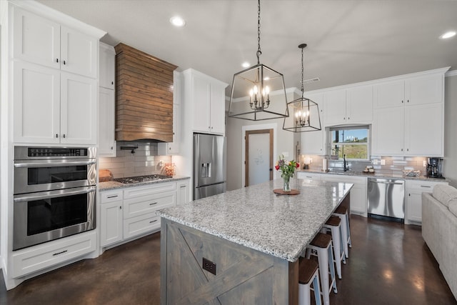 kitchen featuring hanging light fixtures, appliances with stainless steel finishes, white cabinetry, and a center island