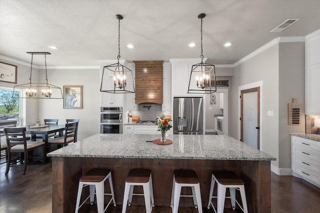 kitchen with white cabinetry, a breakfast bar area, stainless steel appliances, a spacious island, and decorative light fixtures