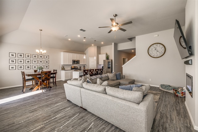 living room with ceiling fan with notable chandelier and dark hardwood / wood-style floors