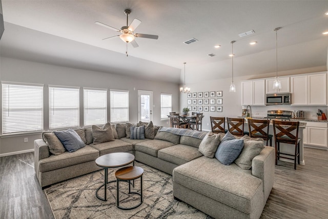 living room featuring ceiling fan with notable chandelier, hardwood / wood-style flooring, a healthy amount of sunlight, and sink