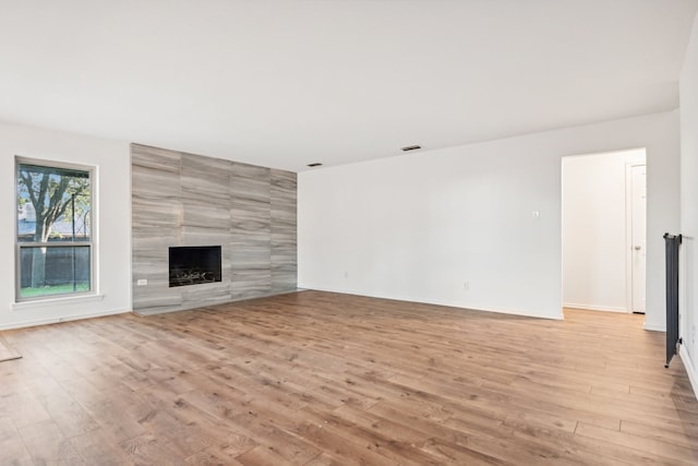 unfurnished living room featuring light wood-type flooring and a tile fireplace