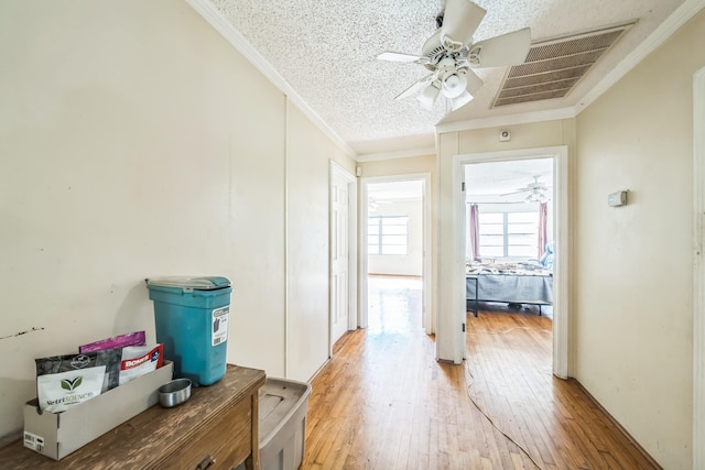 hall with wood-type flooring, a textured ceiling, and crown molding