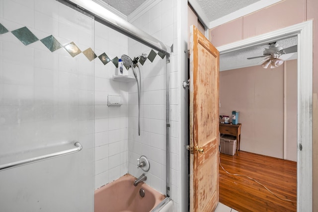 bathroom with ceiling fan, ornamental molding, a textured ceiling, hardwood / wood-style flooring, and tiled shower / bath