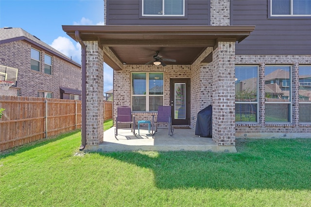 exterior space with a ceiling fan, a patio area, brick siding, a fenced backyard, and a lawn