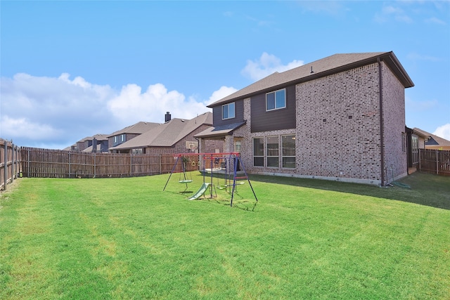 rear view of property with a lawn and a playground