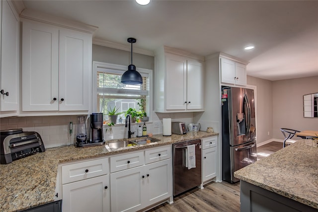 kitchen featuring appliances with stainless steel finishes, backsplash, sink, pendant lighting, and white cabinets