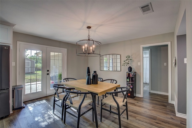 dining area featuring a textured ceiling, french doors, a chandelier, and dark hardwood / wood-style floors