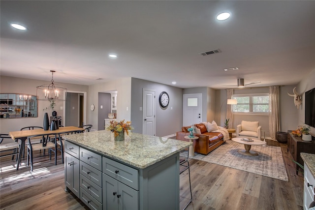 kitchen with visible vents, gray cabinetry, open floor plan, wood finished floors, and a center island