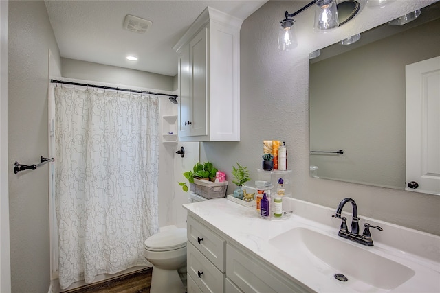 bathroom featuring wood-type flooring, a textured ceiling, toilet, vanity, and a shower with shower curtain