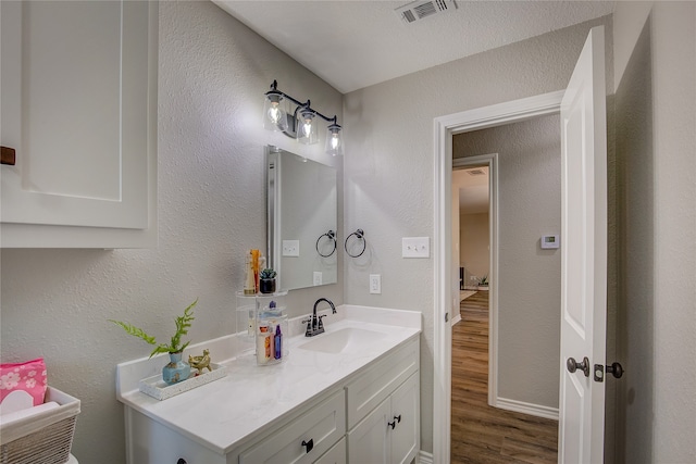 bathroom with hardwood / wood-style floors, vanity, and a textured ceiling