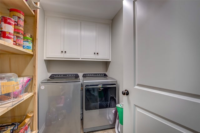 clothes washing area featuring cabinets and separate washer and dryer