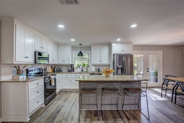 kitchen featuring pendant lighting, white cabinetry, light hardwood / wood-style flooring, and stainless steel appliances