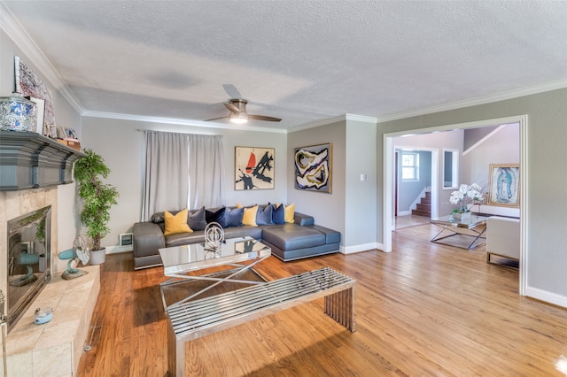 living room with ceiling fan, a textured ceiling, hardwood / wood-style floors, and crown molding