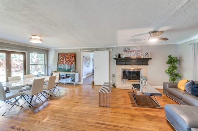 living room with a barn door, crown molding, a textured ceiling, and light hardwood / wood-style flooring