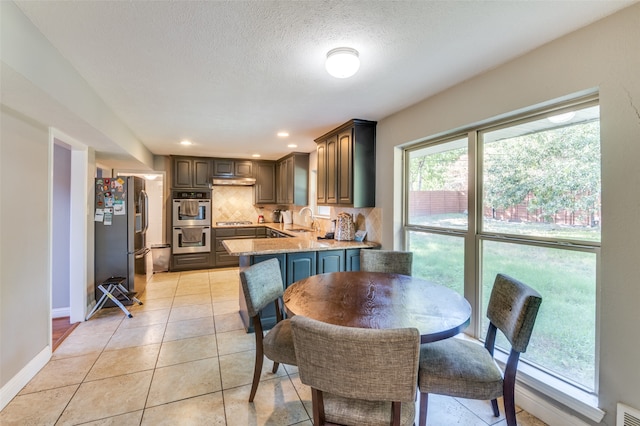 dining space featuring light tile patterned flooring, sink, and a textured ceiling