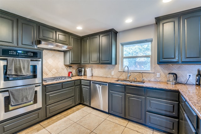 kitchen featuring light stone counters, light tile patterned flooring, sink, stainless steel appliances, and backsplash