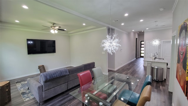 living room with ceiling fan with notable chandelier, ornamental molding, and dark hardwood / wood-style flooring