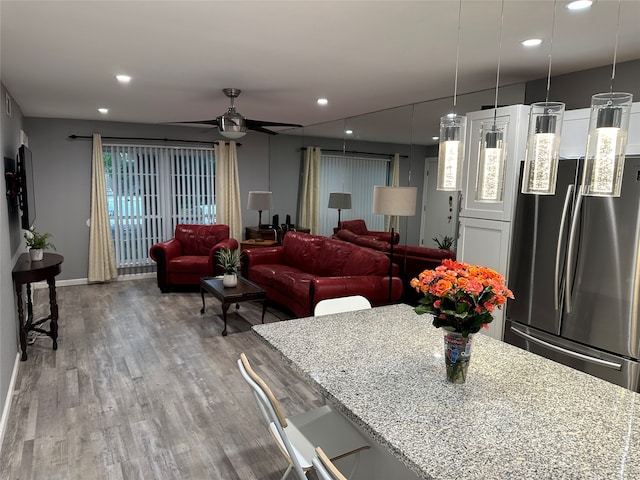 kitchen with light stone countertops, decorative light fixtures, and stainless steel fridge