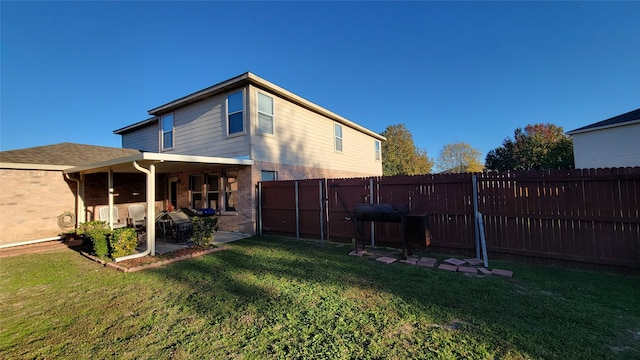 rear view of property featuring a lawn and a patio area