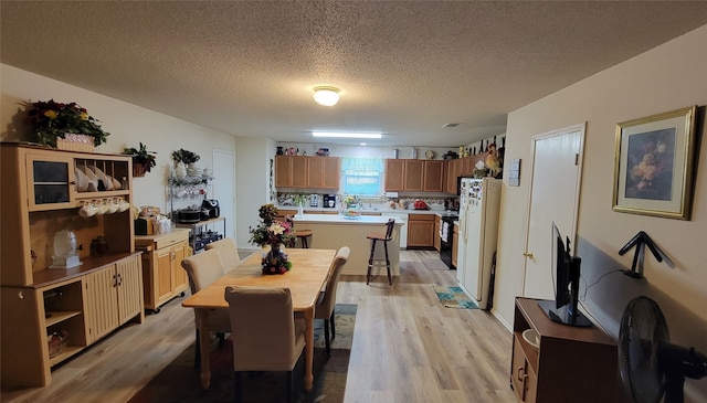 dining area featuring a textured ceiling and light hardwood / wood-style flooring