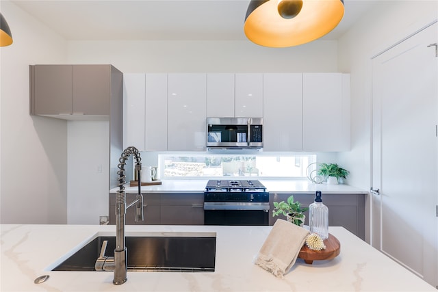 kitchen with stainless steel appliances, white cabinetry, and sink