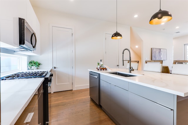 kitchen with sink, hanging light fixtures, light wood-type flooring, dishwasher, and black gas stove