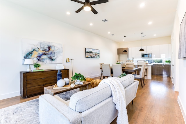 living room with ceiling fan and light hardwood / wood-style flooring