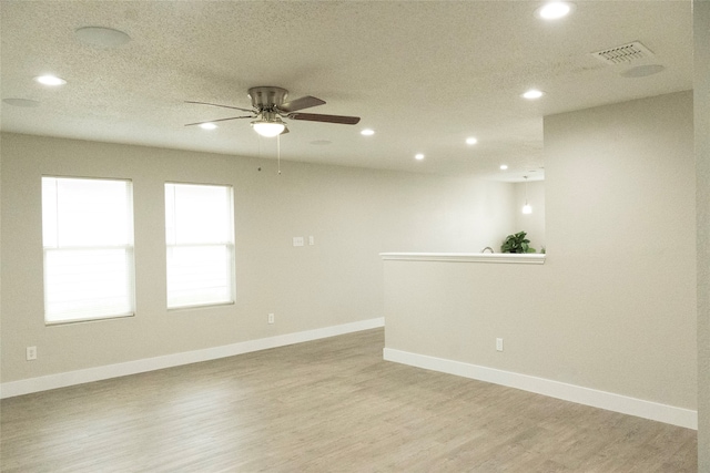 empty room featuring light hardwood / wood-style floors, ceiling fan, and a textured ceiling