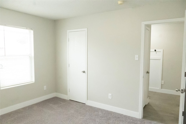 unfurnished bedroom with light carpet and multiple windows