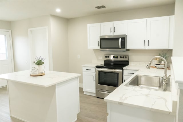 kitchen featuring light stone countertops, light hardwood / wood-style floors, appliances with stainless steel finishes, and sink