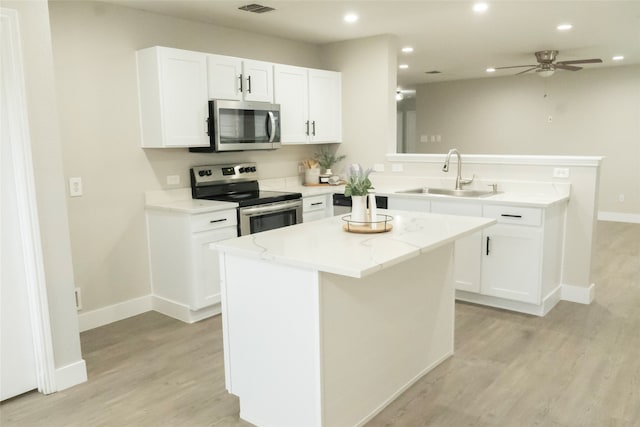 kitchen featuring white cabinets, appliances with stainless steel finishes, sink, and a center island