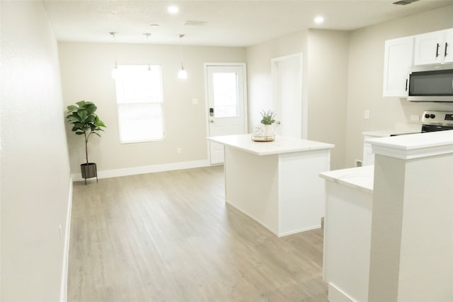 kitchen featuring pendant lighting, a kitchen island, light hardwood / wood-style flooring, white cabinetry, and electric stove