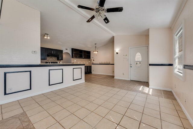 interior space with lofted ceiling with beams, ceiling fan, light tile patterned floors, tasteful backsplash, and kitchen peninsula